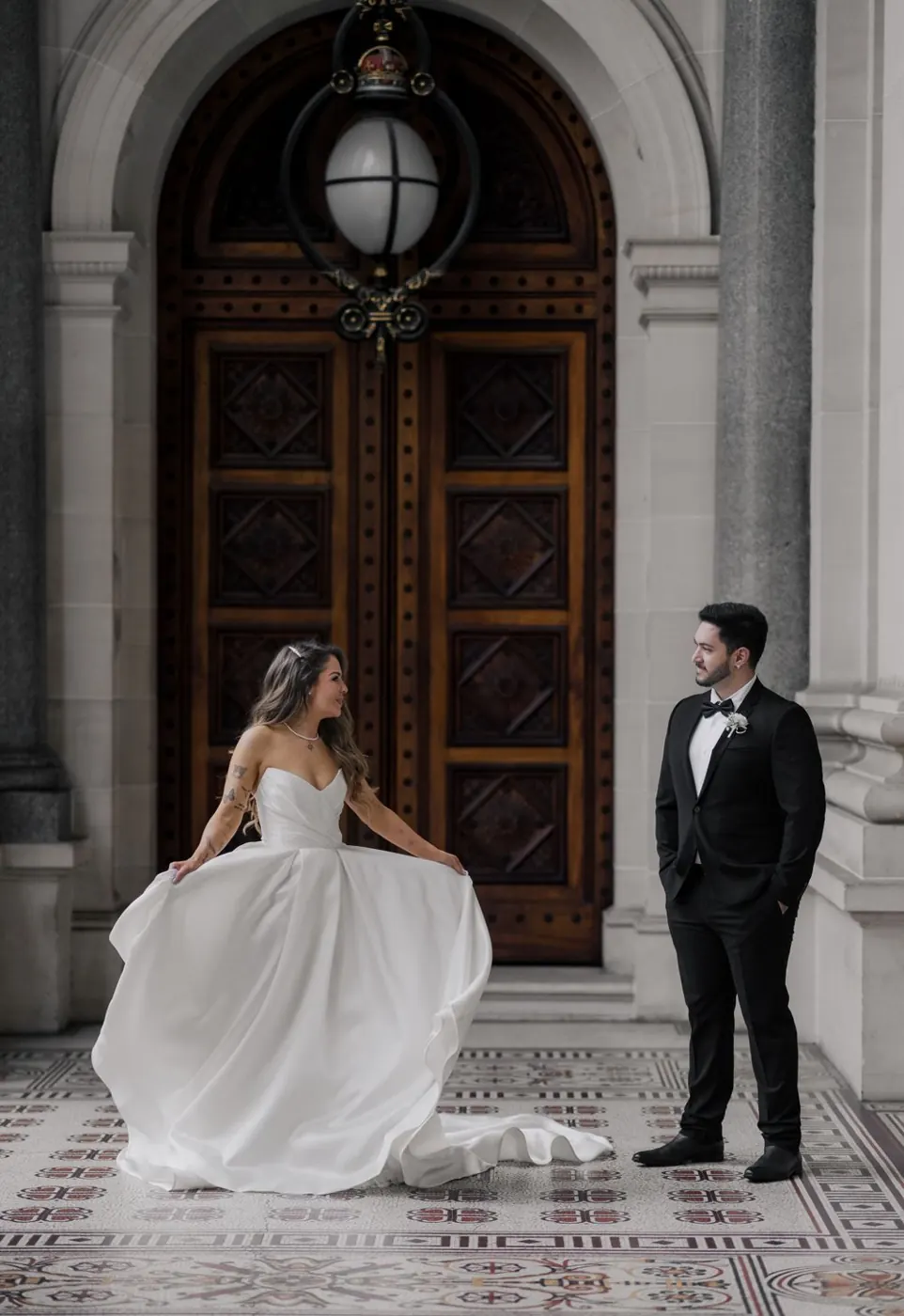 A bride and groom sharing a quiet portrait outside an ornate heritage entrance.