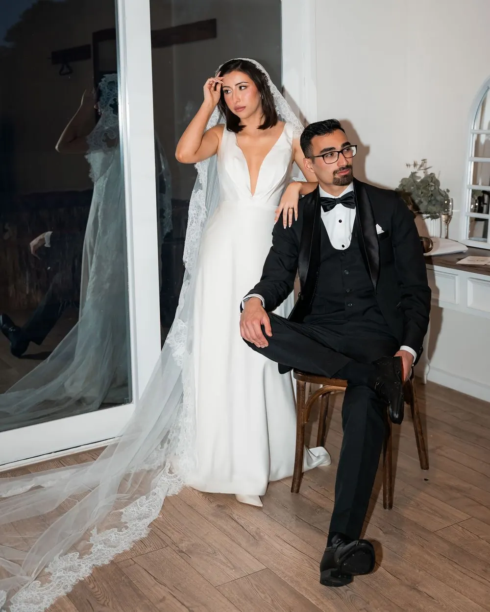 A bride standing beside her seated groom during an editorial wedding portrait.